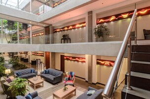 Un vestíbulo amplio con techo alto, una escalera y varias zonas de estar.