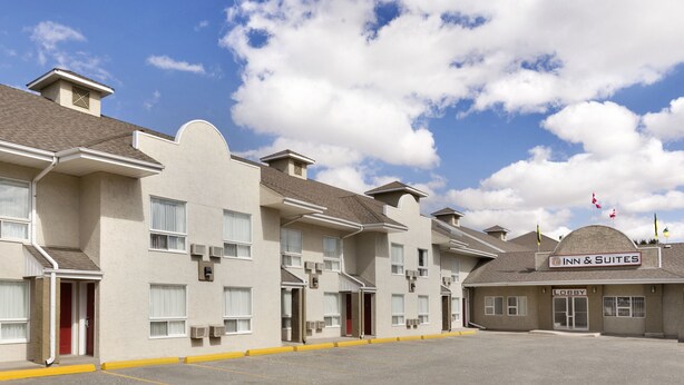 A hotel with multiple units, a lobby, and a parking lot. - Colonial Square Inn & Suites (Saskatoon)