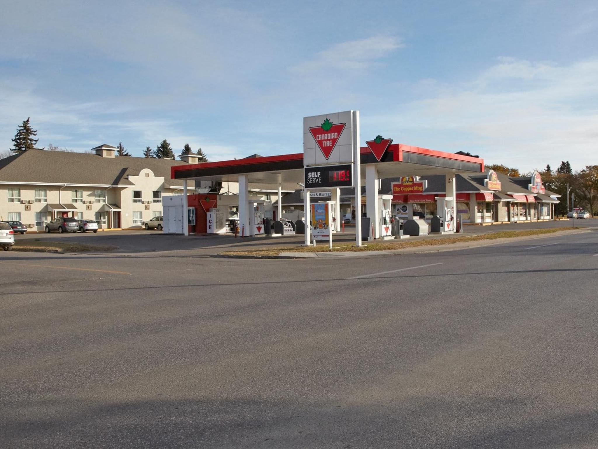Eine Canadian Tire Tankstelle mit einer Selbstbedienungszapfsäule, einem Kiosk und einem Motel im Hintergrund.