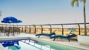 A rooftop pool area with lounge chairs and umbrellas, overlooking a cityscape. - Hotel Nacional Inn Rio Copacabana (Rio de Janeiro)