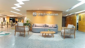 A modern hotel lobby with a curved reception desk, a sofa, and two armchairs. - Hotel Nacional Inn Rio Copacabana (Rio de Janeiro)