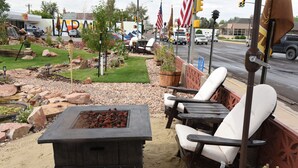 An outdoor seating area with a fire pit, white cushioned chairs, and a decorative fence. - Travel Inn (Laramie)