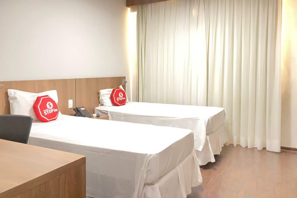 Hotellihuone, jossa on kaksi sänkyä, työpöytä ja puhelin.