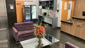 A hotel lobby with a reception desk, a refrigerator, vending machines, and a purple sofa. - Stop Inn Cristiano Machado (Belo Horizonte)