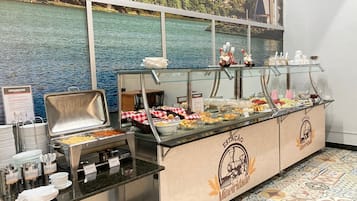 Un bufé con diversos alimentos y un hermoso paisaje de un lago y edificios.