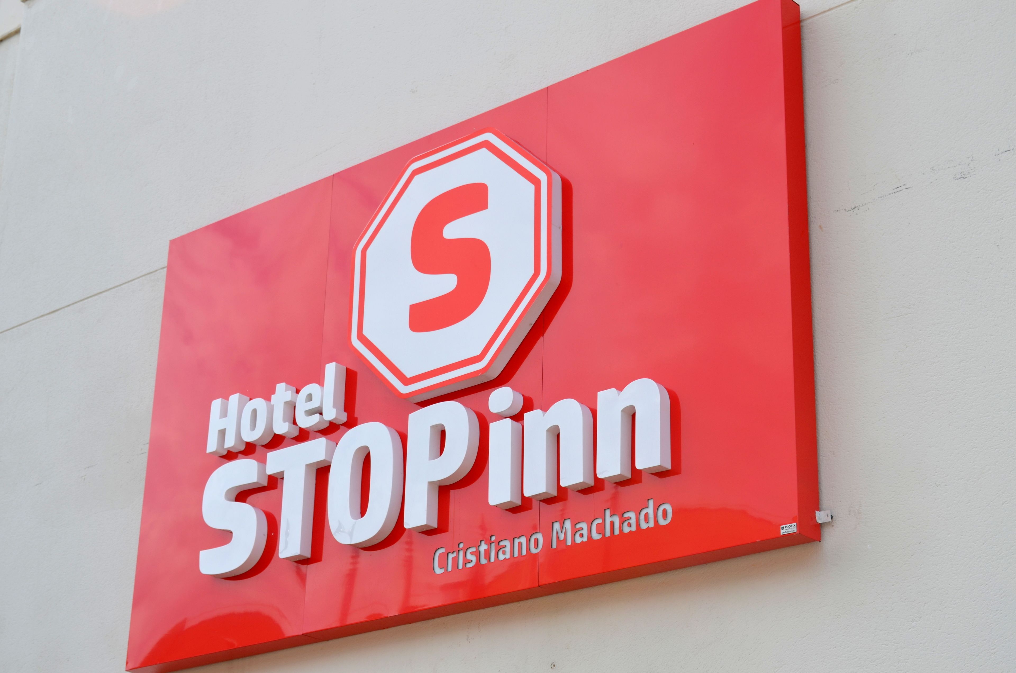 Placa Hotel STOPinn com fundo vermelho e letras brancas.