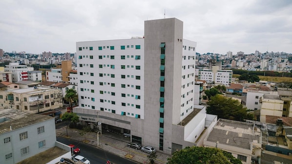 A multi-story hotel with a central tower, surrounded by other buildings. - Ímpar Suítes Expominas (Belo Horizonte)