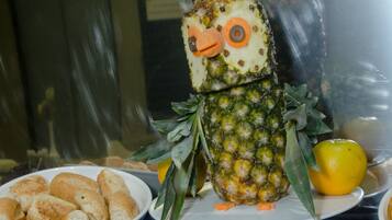 A buffet table with various food items including rolls, pastries, and a creatively decorated pineapple.
