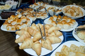 A buffet with various baked goods including croissants, bread rolls, and pastries. - Ímpar Suítes Expominas (Belo Horizonte)