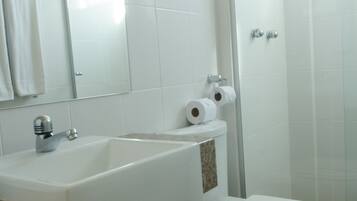 Un baño con lavamanos, inodoro y ducha blancos.