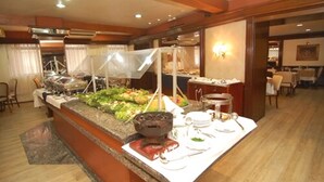 A buffet setup with a variety of food items, a coffee station, and a seating area with tables and chairs. - City Hotel Porto Alegre (Porto Alegre)