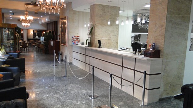 A hotel lobby with a reception desk, seating area, and a chandelier. - City Hotel Porto Alegre (Porto Alegre)