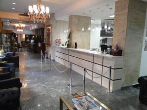 A hotel lobby with a reception desk, seating area, and a chandelier. - City Hotel Porto Alegre (Porto Alegre)