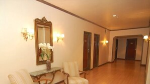 A hallway with two upholstered chairs, a mirror, and wall sconces. - City Hotel Porto Alegre (Porto Alegre)