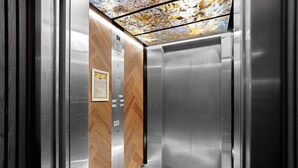 Un ascenseur doté d’un panneau en bois et d’une finition métallique, avec un plafond au motif texturé.