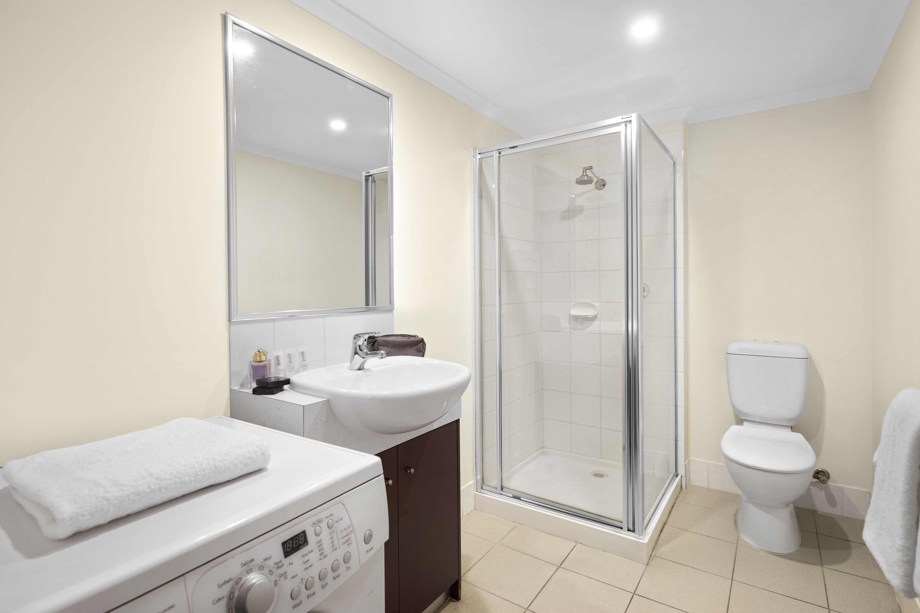 A bathroom with a white sink, a mirror, a shower enclosure, and a toilet.