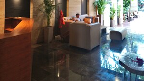 Eine moderne Lobby mit einer Rezeption, einer Sitzecke und großen Fenstern.