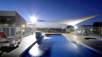Una piscina al aire libre, sombrillas, tumbonas
