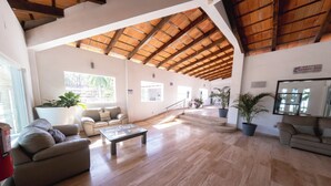 A spacious hotel lobby with a high wooden ceiling, a central coffee table, and a seating area with sofas. - Hotel Splash Inn Nuevo Vallarta (Nuevo Nayarit)