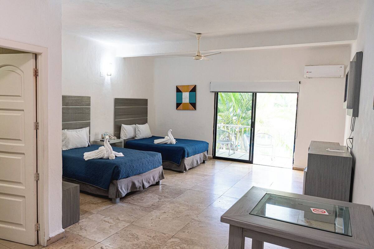 Ein Hotelzimmer mit zwei Betten, einem Balkon mit Blick, einem Fernseher und einem Schreibtisch.