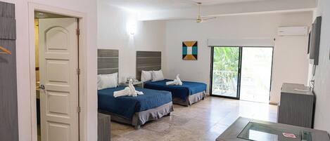 A hotel room with two beds, a balcony with a view, a TV, and a desk.
