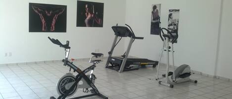 A gym with a stationary bike, elliptical, and treadmill.