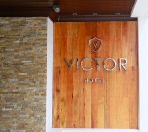 A wooden sign with "VICTOR HOTEL" and a shield logo. - The Victor Hotel (Makati)