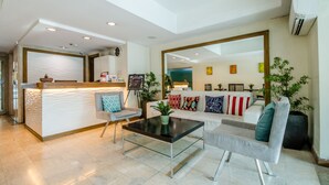 A modern hotel lobby with a reception desk, seating area, and a large mirror. - The Victor Hotel (Makati)