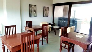 A dining area with wooden tables and chairs, a glass partition, and two abstract paintings on the wall. - The Victor Hotel (Makati)