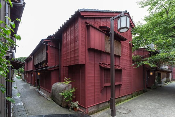 Un bâtiment traditionnel de couleur rouge, doté d’un toit en pente, d’une lanterne et situé dans une rue étroite.