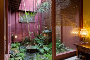 Un jardín japonés tradicional con un farol de madera, un pequeño estanque y abundante vegetación.