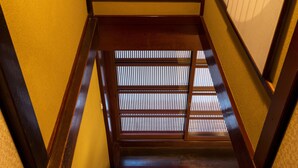 Una escalera de madera con diseño tradicional japonés, que incluye suelo de tatami y pared con puertas shoji.