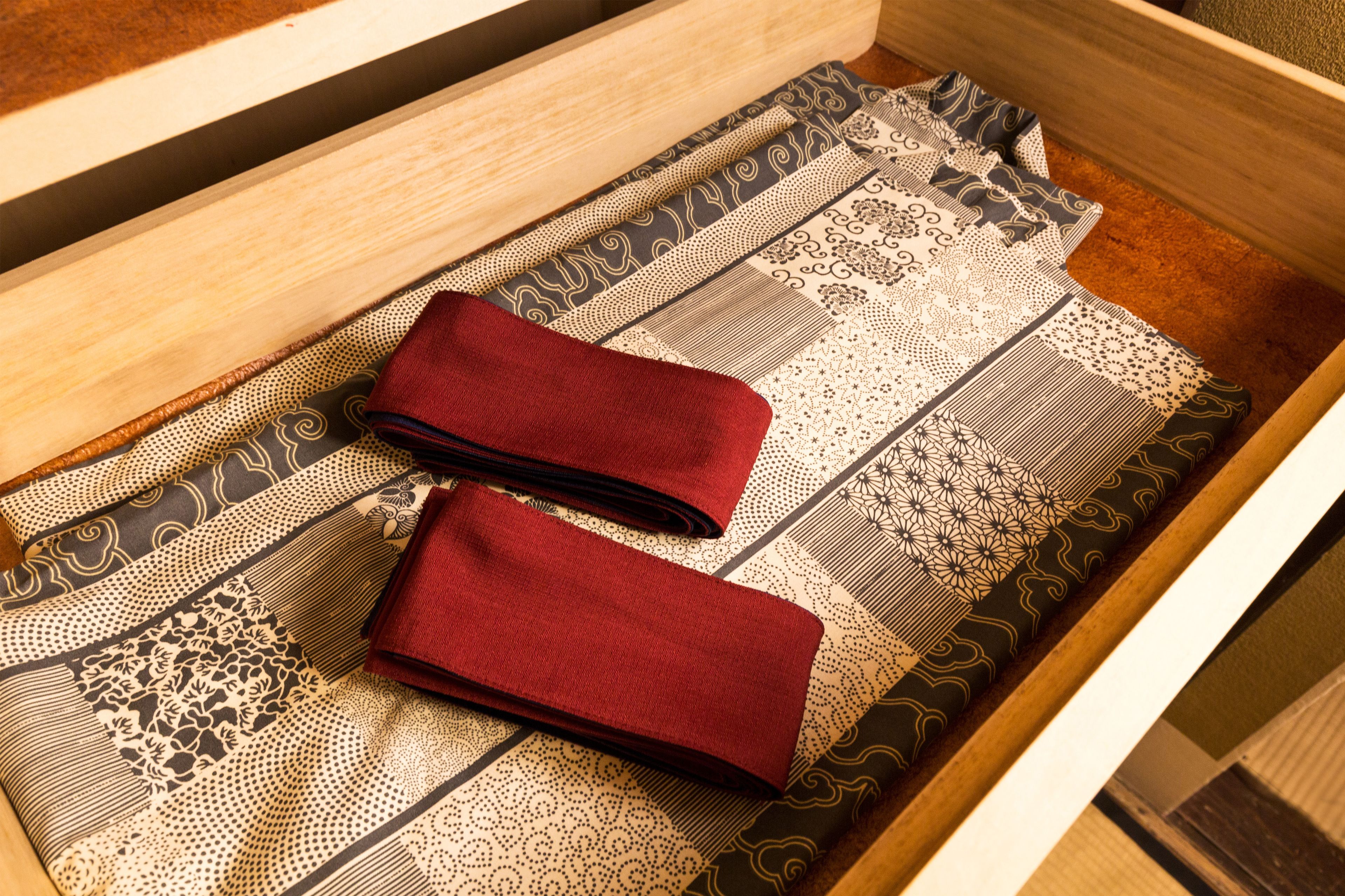 A drawer with neatly folded red napkins and a patterned table runner.