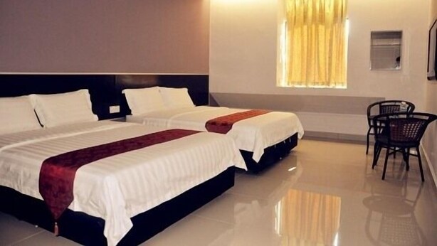 A hotel room with two beds, a window with curtains, a chair, and a small table. - Stay Inn Hotel (Kota Kinabalu)