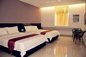 A hotel room with two beds, a window with curtains, a chair, and a small table. - Stay Inn Hotel (Kota Kinabalu)