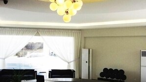 A modern living room with a round dining table, black sofas, and a chandelier. - Goldenhill Hotel (Kota Kinabalu)