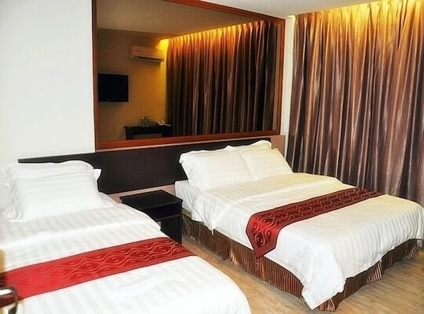 Habitación de hotel con dos camas, un espejo grande y un cabecero de madera.