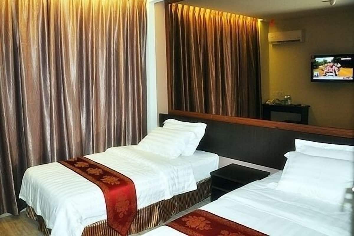 A hotel room with two beds, a large mirror, and a television on the wall.