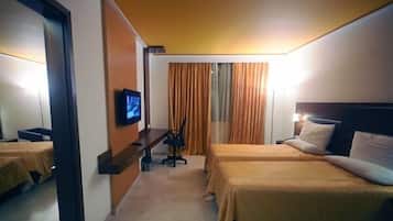 A hotel room with two beds, a desk, a television, and curtains.
