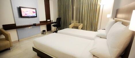 A hotel room with two beds, a TV mounted on the wall, a chair, and a curtain.