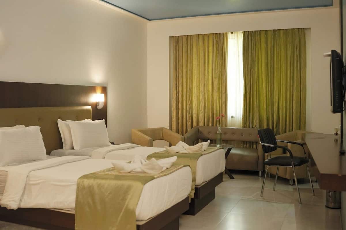 Habitación de hotel con una cama grande, un sofá, un escritorio y una televisión.