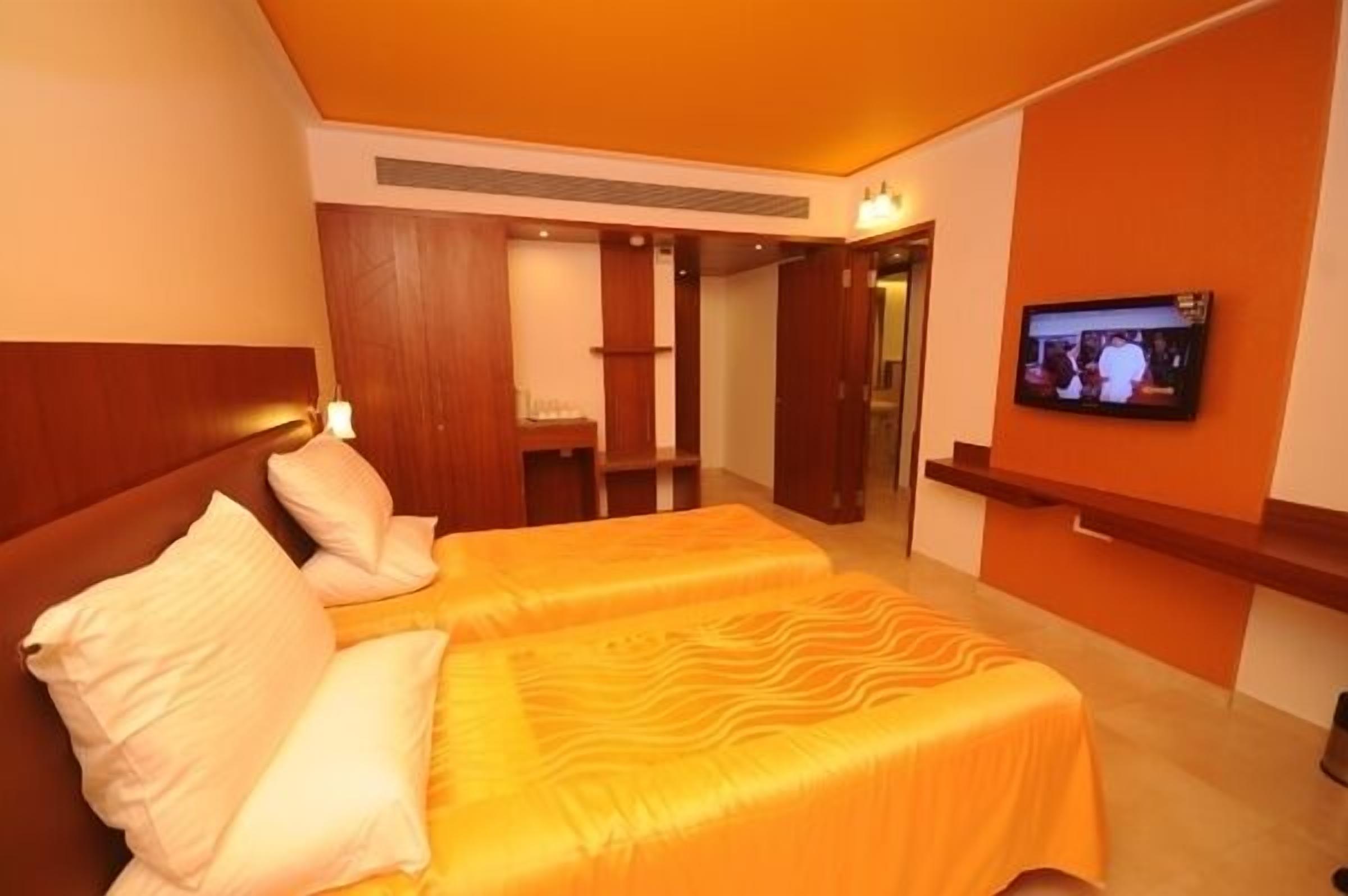 Een hotelkamer met twee bedden, een televisie en een houten hoofdeinde.