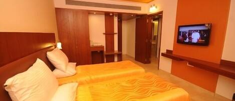 A hotel room with two beds, a television, and a wooden headboard.