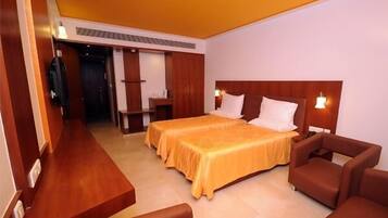A hotel room with two beds, a wooden desk, and a seating area with chairs.