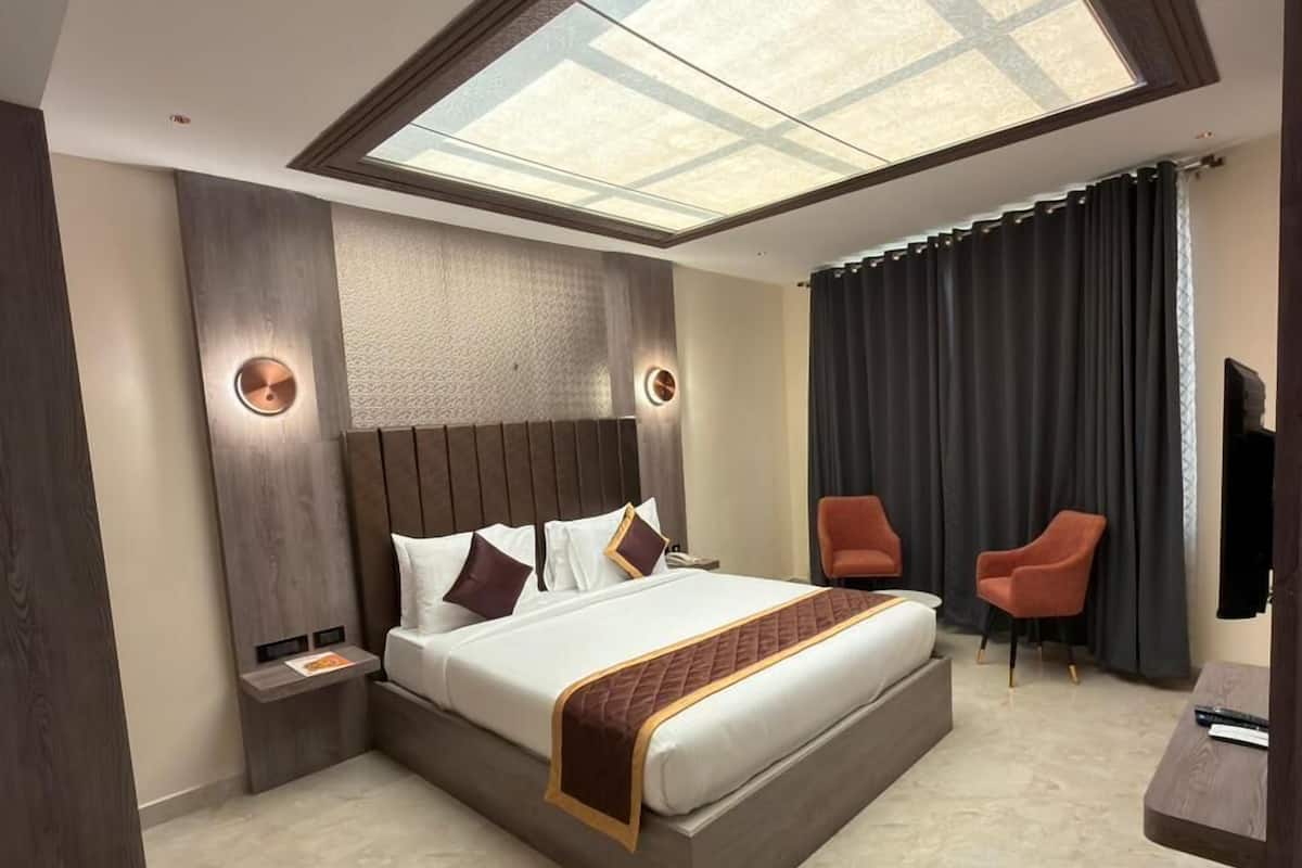 Un dormitorio moderno con tragaluz, una cama grande, dos sillas y una mesita.
