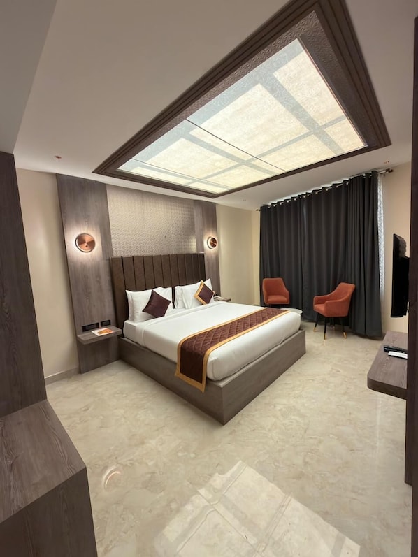 A modern bedroom with a skylight, a large bed, two chairs, and a small table.
