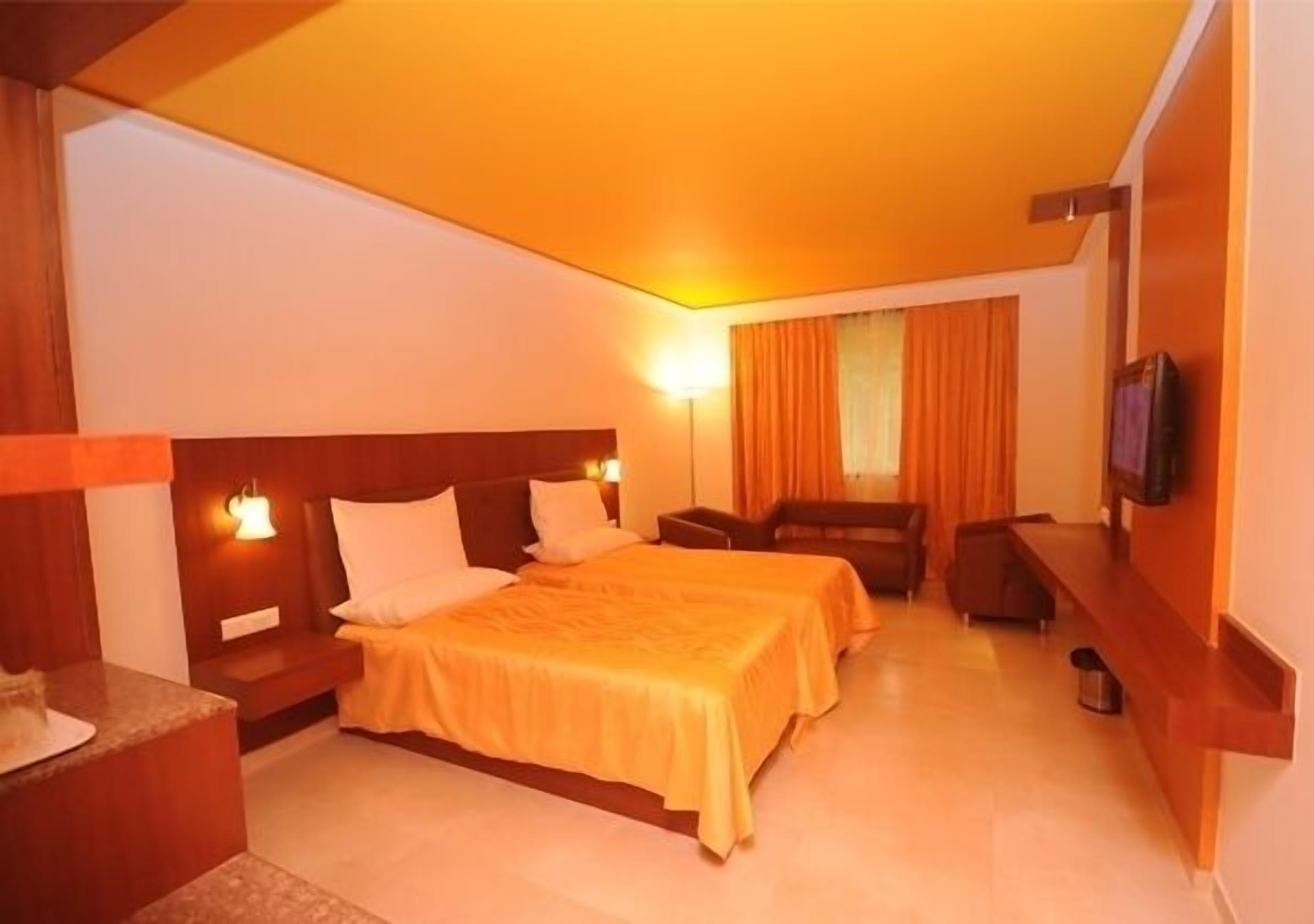 A hotel room with two beds, a TV, a desk, and a chair.