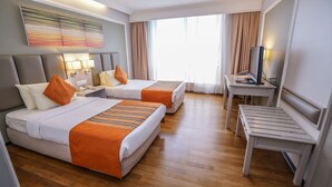 A hotel room with two beds, a desk, a television, and a large window with curtains. - Kingwood Hotel (Kuching)