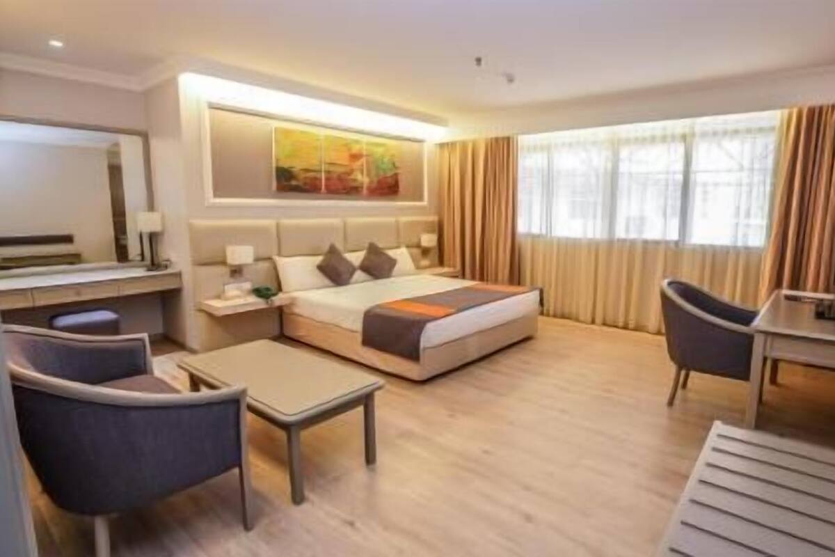 Habitación de hotel con una cama, un escritorio, una silla, una mesita y un televisor.