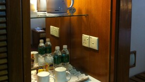 A compact kitchenette with a coffee maker, water bottles, and mugs on a tray. - Kingwood Hotel (Kuching)